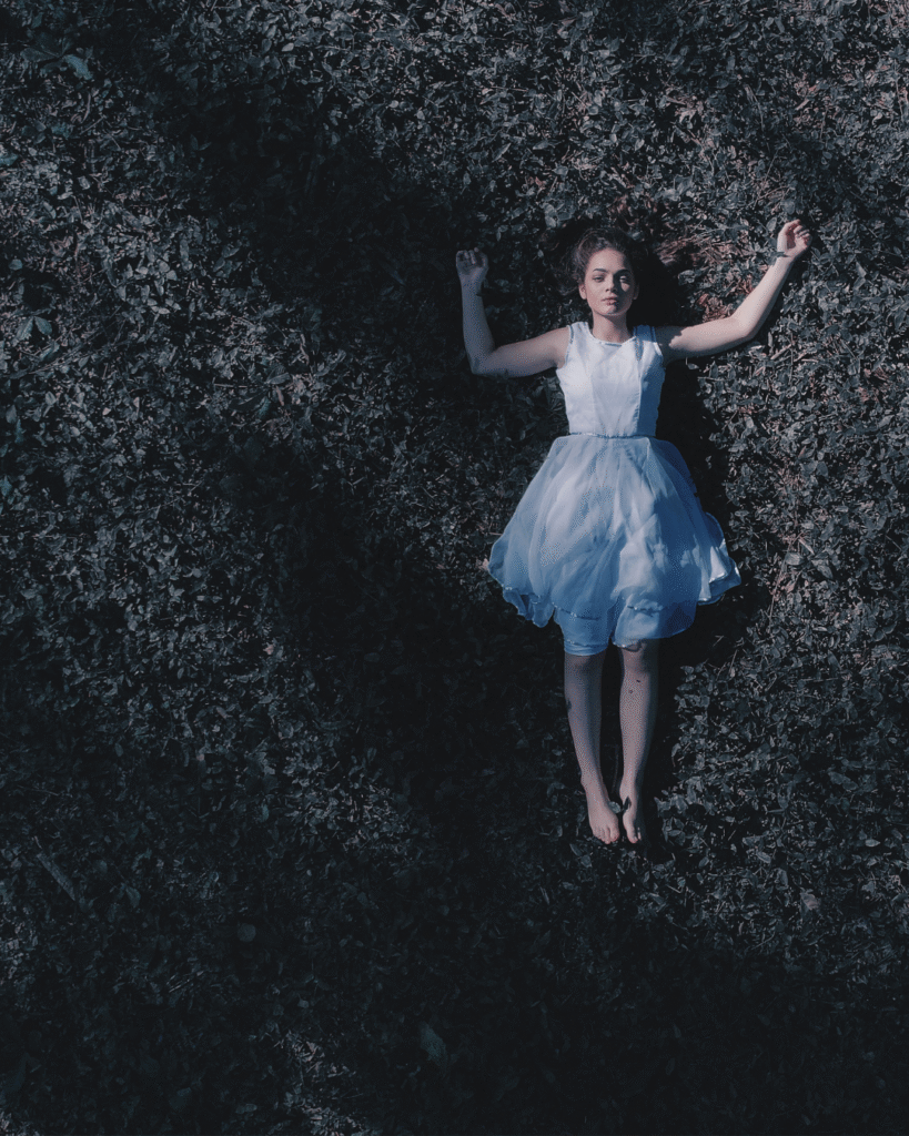 Woman laying in the grass under a shady tree